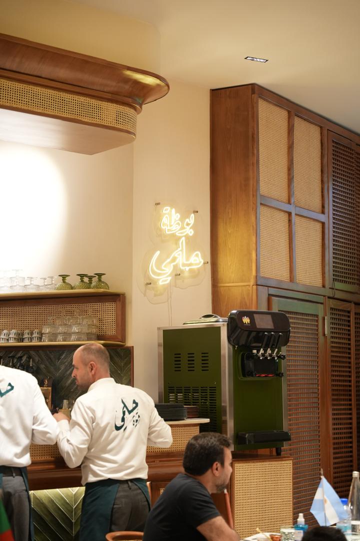 Helmi Cafe service counter with neon Arabic signage in Damascus